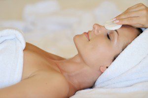 A woman is getting her face washed with soap.